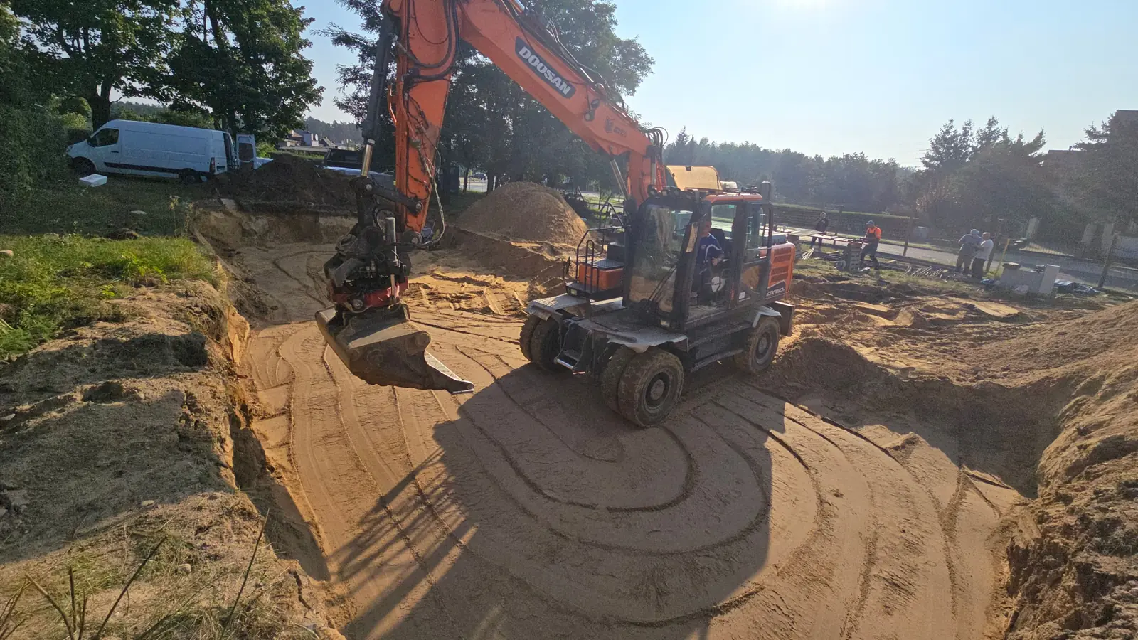Koparka kołowa wyrównuje dno wykopu pod płytę fundamentową