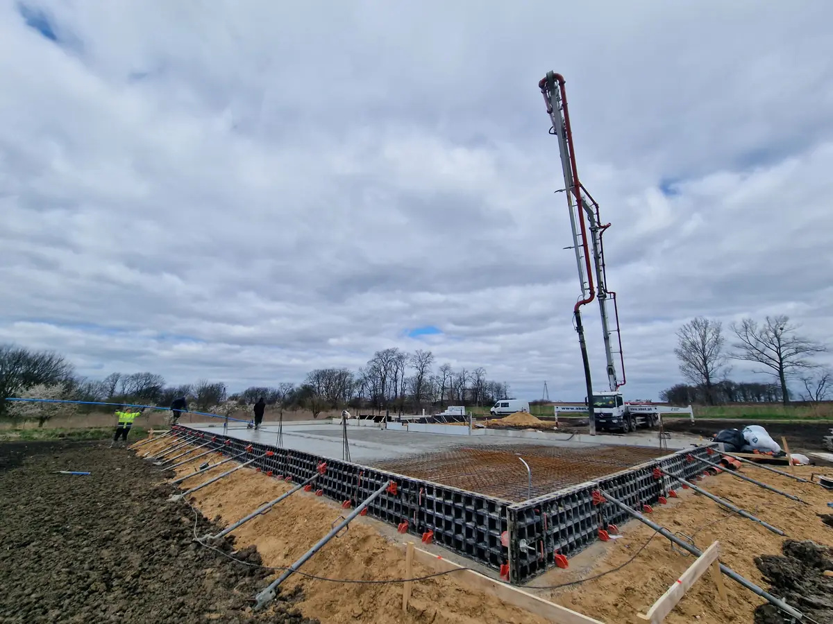 Pompa do betonu podaje mieszankę na zbrojenie płyty fundamentowej w szalunku systemowym