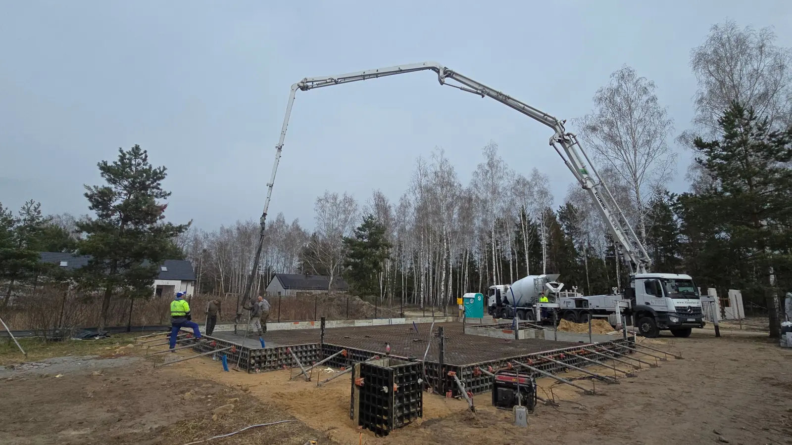 Pompa do betonu nad płytą fundamentową w szalunku systemowym, działka wśród drzew