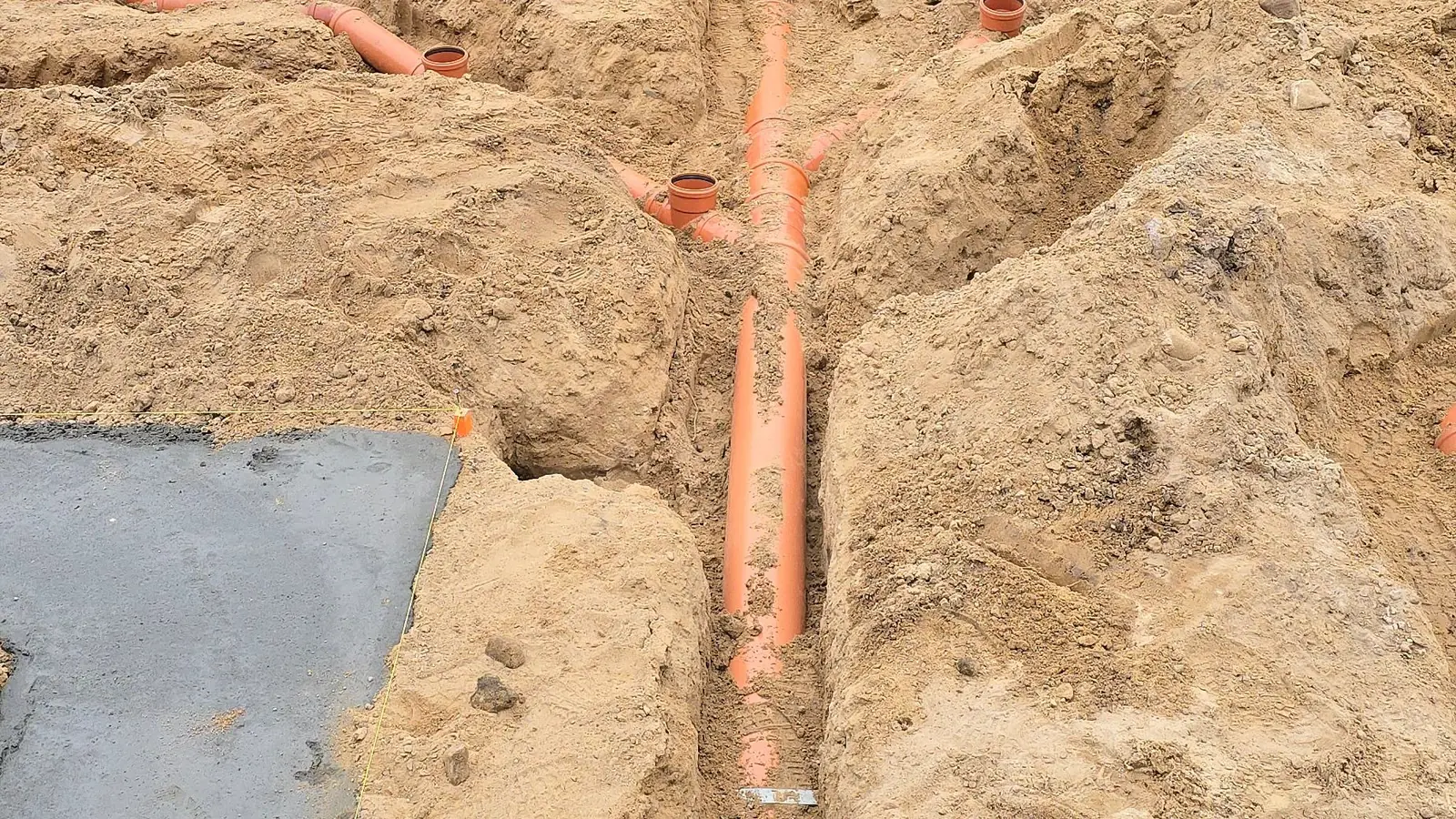 Rura kanalizacji podposadzkowej w wykopie w piaskowej podbudowie pod płytę fundamentową